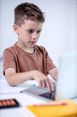 Uzaktan öğrenme çevrimiçi eğitim. Bir okul çocuğu evde dizüstü bilgisayar kullanarak ders çalışıyor. Ev uzaklığı öğrenimi.