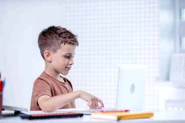 Küçük çocuk ev ödevi olarak dizüstü bilgisayar kullanıyor. Uzaklık eğitimi