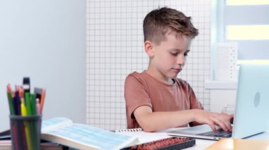 Bilgisayarlı okul çocuğu öğretmen ve sınıf grubuyla görüntülü konuşma yapıyor. Çocuk evden ders çalışıyor. Evde eğitim. Eğitim için modern aletler. Ekran zaman kontrolü. Çevrimiçi uzak öğrenim