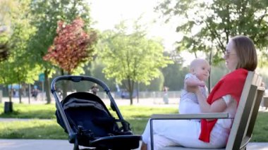 Genç anne ve şirin bebeği parkta bir bankta oturuyor..