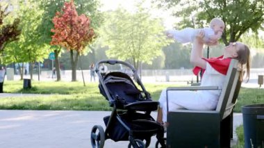 Genç anne ve şirin bebeği parkta bir bankta oturuyor..