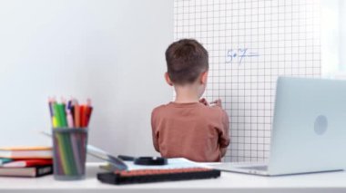 Beyaz tahtada matematik problemleri çözen genç bir çocuğun arka görünüşü