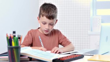 Sevimli öğrenci evde ders çalışıyor. Egzersiz kitabında yazıyor. Ödev yapıyor, evde öğreniyor..