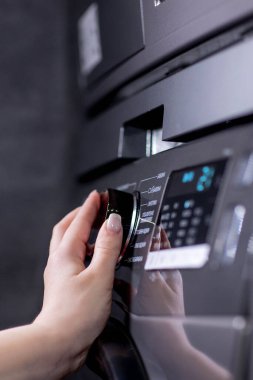 Bulaşık makinesinin kontrol panelindeki düğmelere basan bir kadının yakın çekimi, bir mod seçmesi.