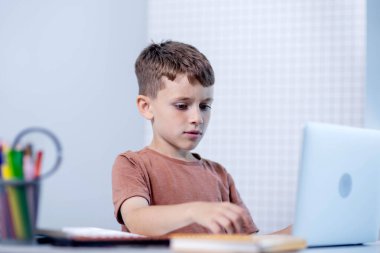 Küçük çocuk ev ödevi olarak dizüstü bilgisayar kullanıyor. Uzaklık eğitimi