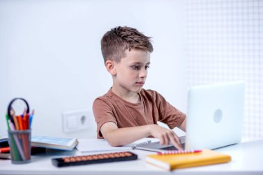 Uzaktan öğrenme çevrimiçi eğitim. Bir okul çocuğu evde dizüstü bilgisayar kullanarak ders çalışıyor. Ev uzaklığı öğrenimi.