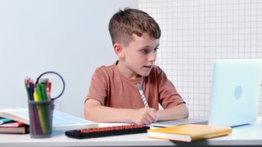 Uzaktan öğrenme çevrimiçi eğitim. Bir okul çocuğu evde dizüstü bilgisayar kullanarak ders çalışıyor. Ev uzaklığı öğrenimi.