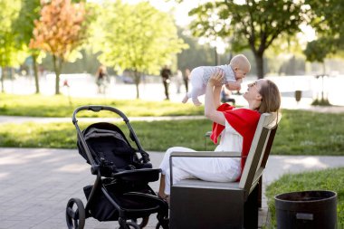 Genç anne ve şirin bebeği parkta bir bankta oturuyor..