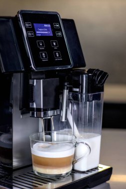 Mutfakta bir fincan cam latte ile modern kahve makinesi..