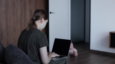 Sevimli küçük erkek bebek, annesinin kanepesinde oturuyor ve internette çalışıyor. Kadın serbest doğum izni alırken para kazanıyor.