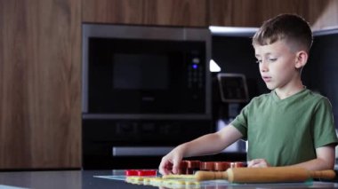 Evdeki mutfakta kurabiye keskisi ve hamur kullanarak kurabiye yapan küçük çocuk..