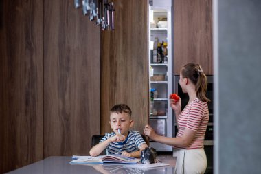 Güzel anne, oğluna ödevlerini yapması için yardım ediyor..