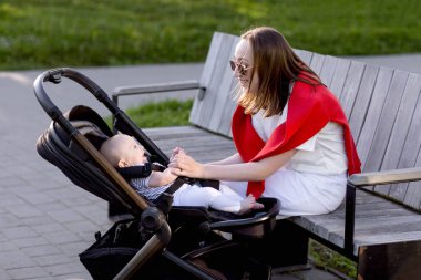 Genç anne ve şirin bebeği parkta bir bankta oturuyor..