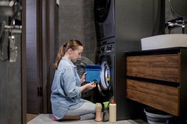 Çamaşır deterjanı kapsülünü çamaşır makinesine koyan kadın, yakın plan. Çamaşır yıkama. Yıkama ve temizlik kavramı..