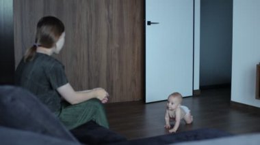 Bebek çocuk koltukta oturan annesine emekliyor..