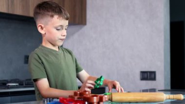 Evdeki mutfakta kurabiye keskisi ve hamur kullanarak kurabiye yapan küçük çocuk..