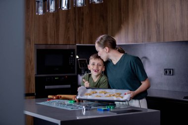 Anne ve oğul mutfakta birlikte yeni yıl kurabiyesi pişiriyorlar. Yeni yıla hazırlık konsepti, Noel tatili..