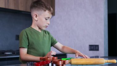 Evdeki mutfakta kurabiye keskisi ve hamur kullanarak kurabiye yapan küçük çocuk..