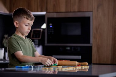 Evdeki mutfakta kurabiye keskisi ve hamur kullanarak kurabiye yapan küçük çocuk..