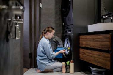 Çamaşır deterjanı kapsülünü çamaşır makinesine koyan kadın, yakın plan. Çamaşır yıkama. Yıkama ve temizlik kavramı..