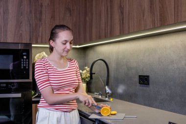 Kadın mutfakta portakal kesiyor..