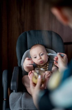 Anne küçük bebeğini mutfakta besliyor. Bebeğin ilk yemeği..