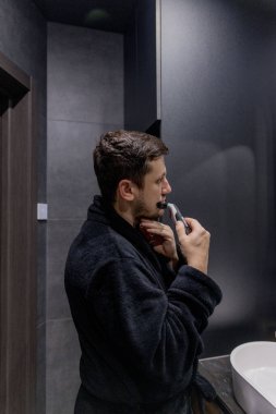 Yakışıklı genç adam sakalını buduyor..