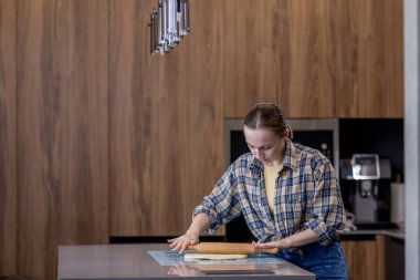 Kadın ustalıkla hamur saçıyor. Mutfakta uzmanlığını gösteriyor..