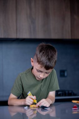 Ev mutfağında zencefilli kurabiye süsleyen tatlı çocuk..