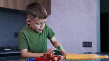 Evdeki mutfakta kurabiye keskisi ve hamur kullanarak kurabiye yapan küçük çocuk..