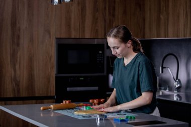 Genç bir kadın, modern ve düzenli görünen şık bir mutfak tezgahında ustalıkla taze hamur hazırlıyor.