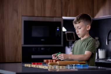 Evdeki mutfakta kurabiye keskisi ve hamur kullanarak kurabiye yapan küçük çocuk..