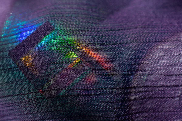 Glass cube with color spectrum rays on fabric. Abstract background with reflection and refraction of light.