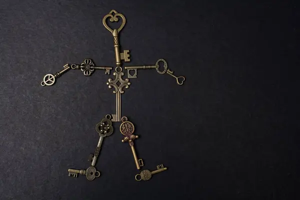 复古金属钥匙在黑色背景上形成一个人的形状 — 图库照片