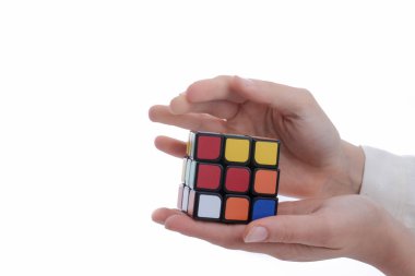 Beyaz arka planda elinde bir Rubik küpünü tutan çocuk