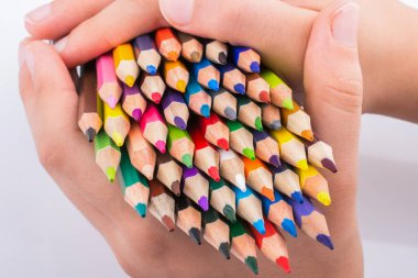 Beyaz arkaplanda el ele tutuşan renkli kalemler