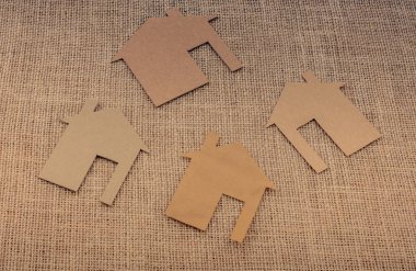 Tuvalin arka planında kağıttan yapılmış küçük bir ev şekli.