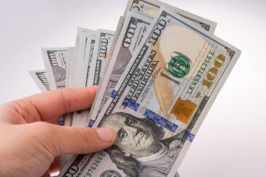 İnsan eli, Amerikan doları banknotunu beyaza izole edilmiş olarak tutuyor.
