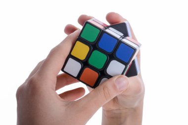 Beyaz arka planda elinde bir Rubik küpünü tutan çocuk