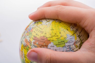 Üzerinde harita olan bir küreyi tutan el.