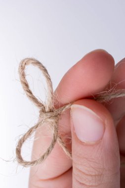 İplik düğüm açık renk arka plan üzerinde elinde