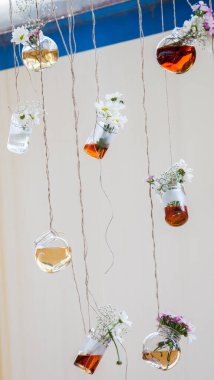 İplere asılı çiçekli bitkisel çay şişeleri
