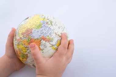 Beyaz bir arka plan üzerinde elinde bir küre tutan çocuk