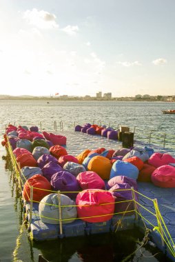 Deniz kenarındaki yüzme platformunda renkli yastıklar.