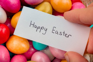 Renkli dekoratif taşlar üzerine küçük bir kağıda yazılmış Paskalyanız kutlu olsun.