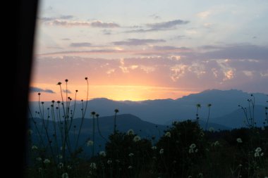 Dağ manzarasında gün batımı. Çayır ve dağ manzarası.