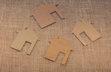 Tuvalin arka planında kağıttan yapılmış küçük bir ev şekli.