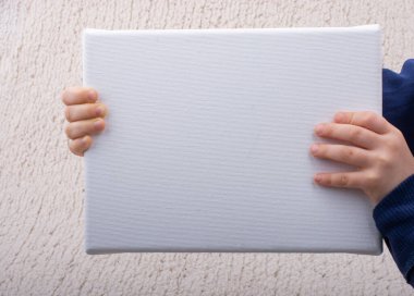 Elinde boş bir tuval olan küçük bir çocuk. Metin için alanı kopyala.