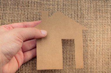 Tuvalin arka planında bir bez evi tutan el.