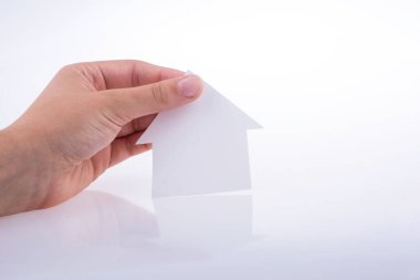 Beyaz bir arka plan üzerinde bir kağıt ev tutan el
